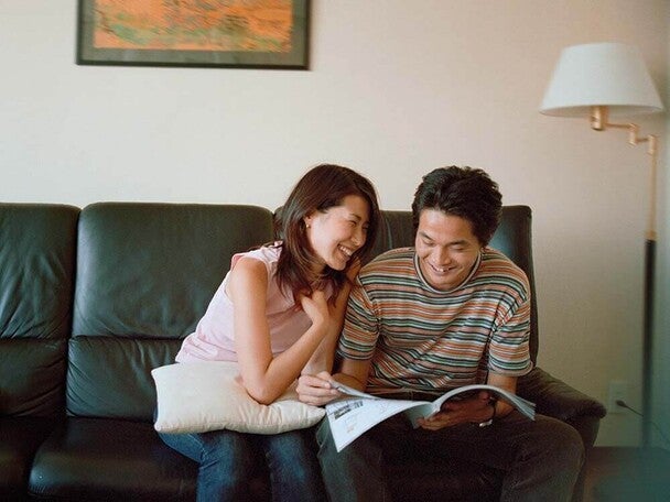 Photo of two people on a couch, smiling and reading a magazine
