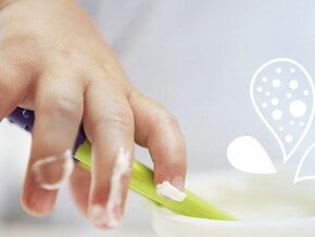 Mano de bebé comiendo puré de verduras