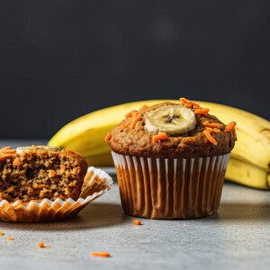 Banana muffin with sliced banana on top, next to peeled muffin and bananas.