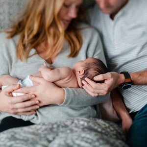 Fotografía: padres sosteniendo con ternura a dos recién nacidos en hogar acogedor