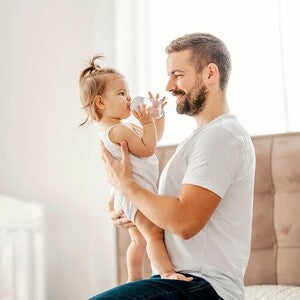 Fotografía: padre sonriente sostiene a su hija pequeña en habitación luminosa