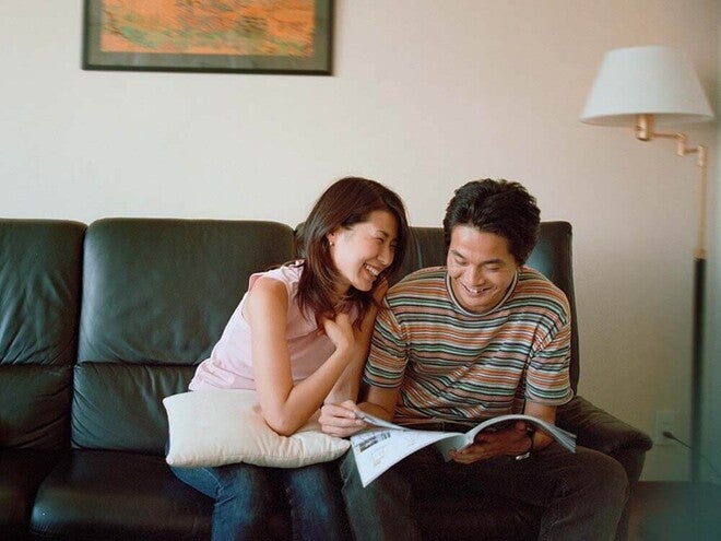 Photo of two people on a couch, smiling and reading a magazine