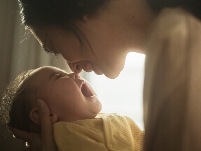 Madre con bebé en brazos junto a una ventana, mirándolo con calma. Luz natural suave, tono científico accesible. Sin biberón ni producto visible, sin logos.